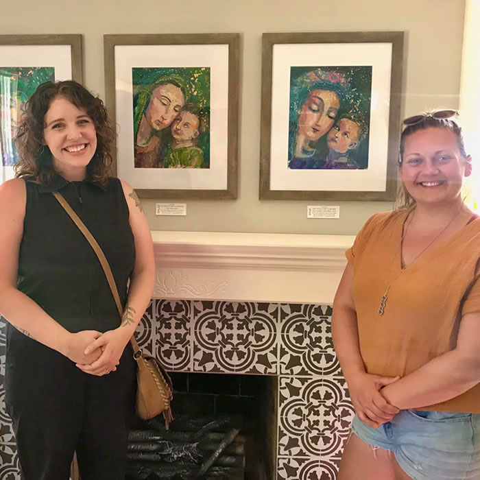 two women next to paintings of Jesus with Mary that they purchased