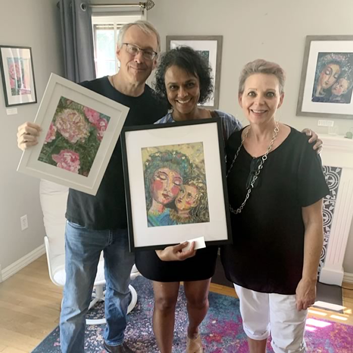 Kat with people holding art of Mary and Jesus and a flower at home studio sale.