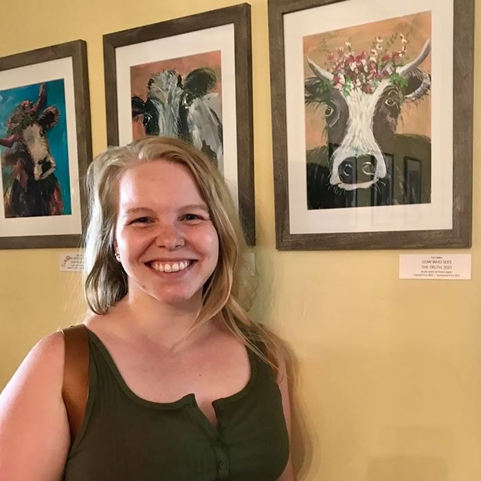 a smiling women next to a painting that she bought